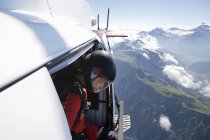 Female sky diver in helicopter checking for exit over mountain, Interlaken, Berne, Switzerland — Stock Photo