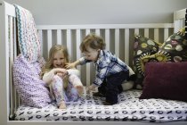 Criança e irmã do sexo masculino brincando na cama dia — Fotografia de Stock