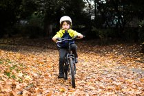 Мальчик в парке в велосипедном шлеме катается на велосипеде — стоковое фото