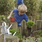 Menino da escola removendo plantas do pote no jardim — Fotografia de Stock