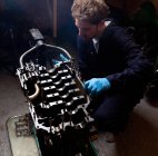 Мужчина-механик анализирует автомобильный двигатель, снятый с автомобиля — стоковое фото