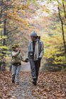 Mother and daughter walking in autumn forest — Stock Photo