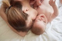Vista aerea della donna sul letto baciare bambino figlio sulla guancia — Foto stock