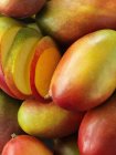 Целые и нарезанные манго, крупным планом — стоковое фото