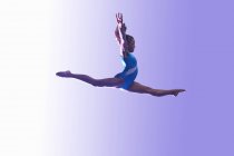 Young gymnast in mid-air leap — Stock Photo