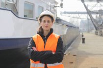 Porträt einer Hafenarbeiterin, die mit verschränkten Armen im Hafenbecken steht — Stockfoto