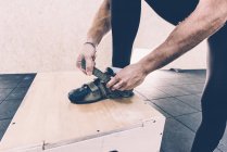 Cropped shot of man fastening trainers in cross training gym — Stock Photo