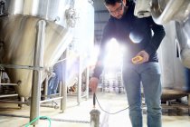 Trabalhador na cervejaria, verificando a temperatura da água no tanque de cerveja — Fotografia de Stock