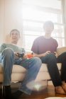 Père et fils jouant au jeu vidéo sur canapé — Photo de stock