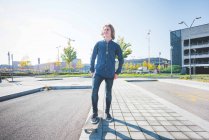 Portrait de jeune skateboarder urbain homme debout regardant loin du trottoir — Photo de stock
