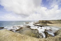 Wide angle shot of rocky seashore with cloudy sky — Stock Photo