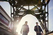 Two young men walking under bridge, Bristol, UK — Stock Photo