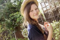 Portrait of teenage girl in straw hat in garden — Stock Photo