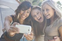 Три юные подруги делают селфи со смартфоном — стоковое фото