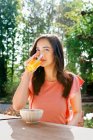 Porträt einer jungen Frau, die Orangensaft im Garten trinkt — Stockfoto
