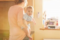 Frau trägt Baby-Sohn im Arm in Küche — Stockfoto