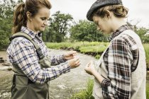 Mother and daughter by river preparing fishing lines — Stock Photo