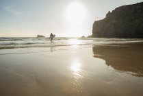Senior woman walking into sea with surfboard, Camaret-sur-mer, Bretagna, Francia — Foto stock
