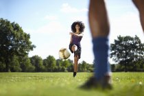Giovane donna calci pallone da calcio verso fidanzato nel parco — Foto stock