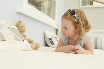 Porträt eines Mädchens, das mit Teddybär auf dem Sitz einer Ferienwohnung liegt — Stockfoto