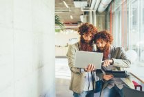 Male adult hipster twins pointing at laptop in office — Stock Photo