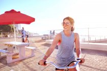 Mujer montar en bicicleta en el paseo marítimo - foto de stock
