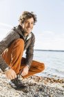 Mann bindet Schnürsenkel am Seeufer — Stockfoto