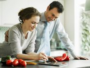 Бизнесмен и жена с помощью цифрового планшета на кухне — стоковое фото