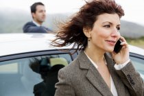 Businesswoman on cell phone, man in background — Stock Photo