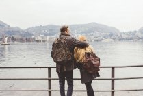 Vista trasera de la pareja joven mirando hacia fuera en el lago, Lago de Como, Italia - foto de stock