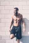 Junger barbusiger männlicher Crosstrainer lehnt vor Turnhalle an Wand — Stockfoto