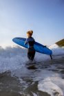 Female surfer running into the ocean — Stock Photo