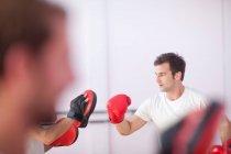 Jeune homme et entraîneur boxe dans la salle de sport — Photo de stock