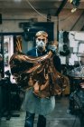 Портрет металлиста, держащего медную продукцию в кузнечном цехе — стоковое фото