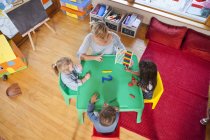 Overhead view of teacher and pupils counting at nursery school — Stock Photo