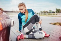 Female runners doing warm up stretches on pier — Stock Photo