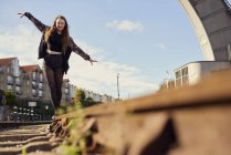 Giovane donna in equilibrio sul binario del treno, vista a basso angolo, Bristol, Regno Unito — Foto stock