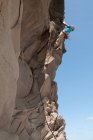 Escalador de rochas escalando penhasco irregular — Fotografia de Stock