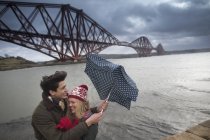 A young couple pose in front of the Forth Rail Bridge in Queensferry, near Edinburgh, Scotland — Stock Photo