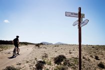 Man mountain biking past sign post, Lanzarote — Stock Photo