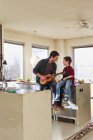 Père et petit fils jouant de la guitare dans la cuisine — Photo de stock
