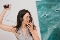 Mujer adulta media escuchando música a través de auriculares - foto de stock