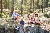 Familia sentada sobre rocas en el bosque - foto de stock