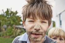 Menino da idade elementar com rosto lamacento com irmão ao ar livre — Fotografia de Stock