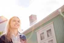 Low angle view of house exterior and blonde haired teenage girl looking away smiling, Reykjavik, Iceland — Stock Photo