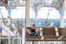 Young boy in train station waiting room playing handheld game — Stock Photo