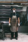 Portrait of male metalworker in dust mask, forge storeroom — Stock Photo