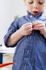 Boy buttoning shirt at home — Stock Photo