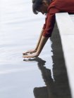 Mulher deitada na frente pendurada no cais tocando a superfície da água, Copenhague, Dinamarca — Fotografia de Stock