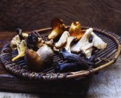 Funghi selvatici biologici in vassoio tessuto su legno — Foto stock